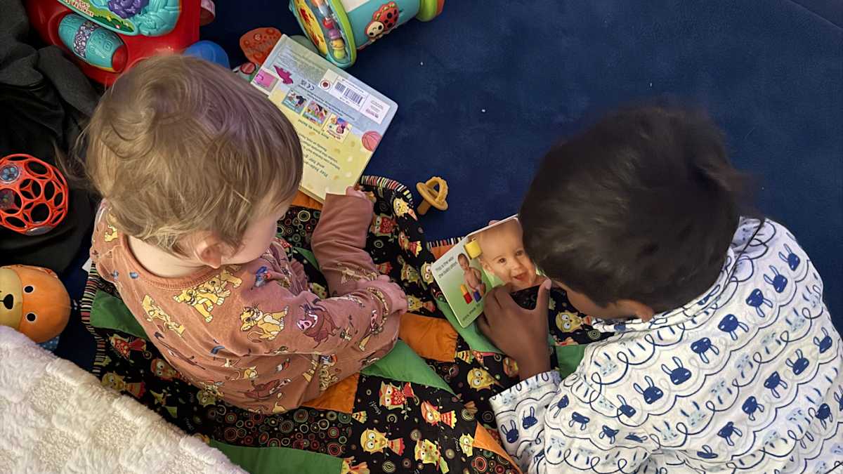 Birds-eye-view of two young people sitting on the floor, reading books together.