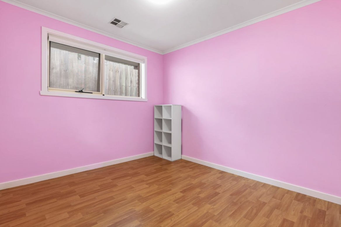 --Empty bedroom with pink walls, floorboards and a cube shelf--