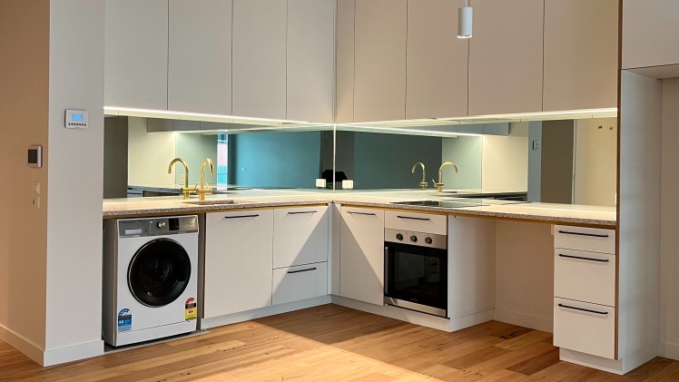 --Brunswick Parklife apartment kitchen with washing machine, oven, induction stove and storage.--