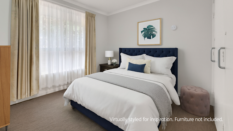 Bedroom with modern navy bed, white bedding, bedside table with lamp, wall art, and beige curtains.