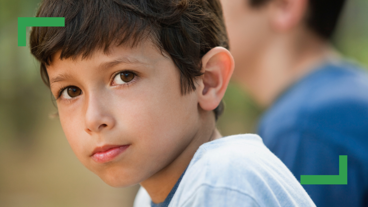 Close up of a young boy with brown hair wearing a white t-shirt.