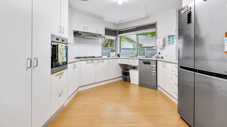 Spacious kitchen with white cabinetry, stainless-steel appliances and a large window overlooking the yard.
