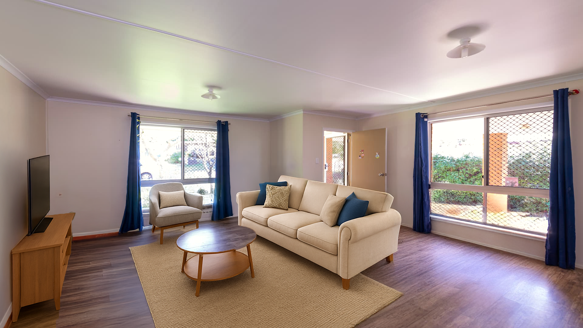 --Combined lounge and dining space with two arm chairs, a TV on a TV unit and a wooden table with a chair.--