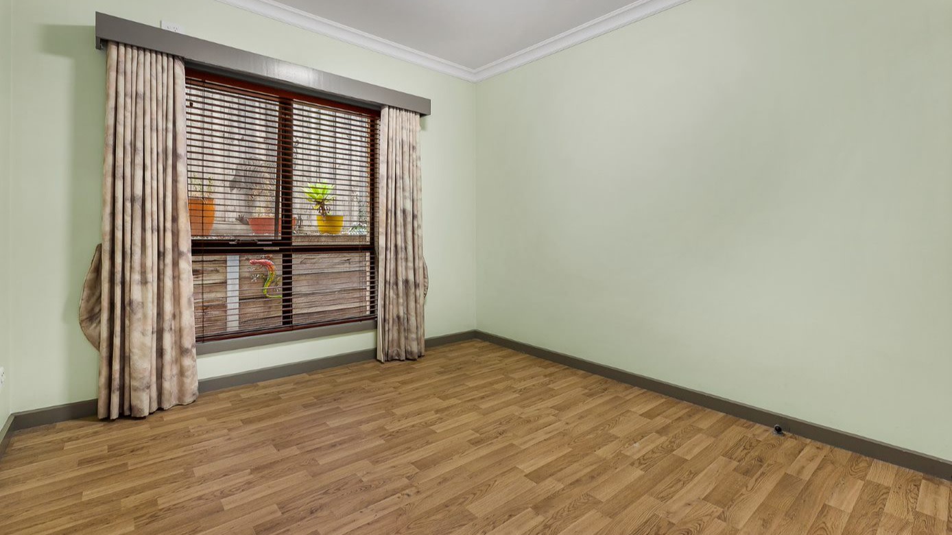 --Empty bedroom with wooden floor boards, a large window with curtains and a pale green walls.--