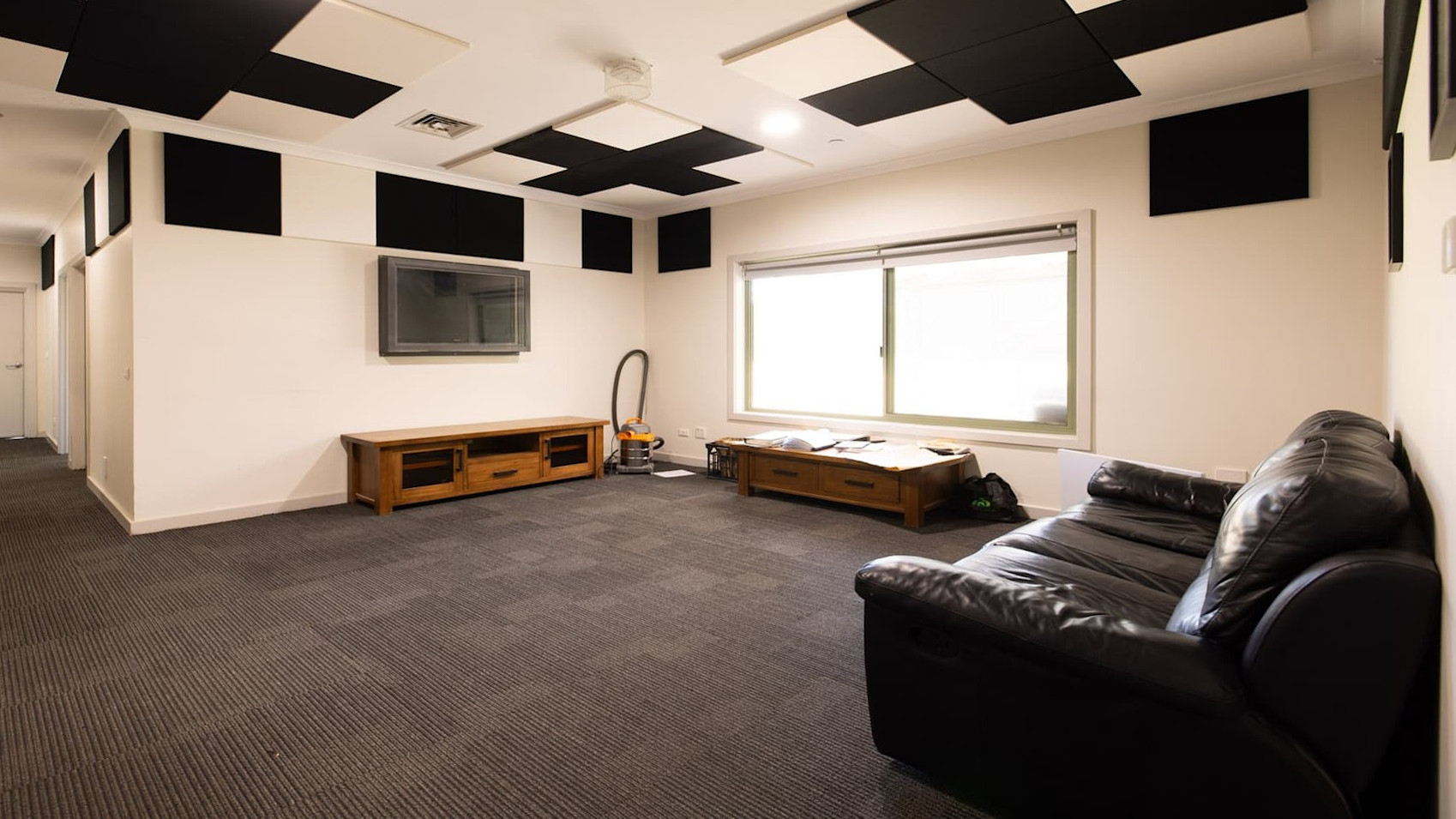 Second living space with grey carpet, lounge, window and wall mounted television.