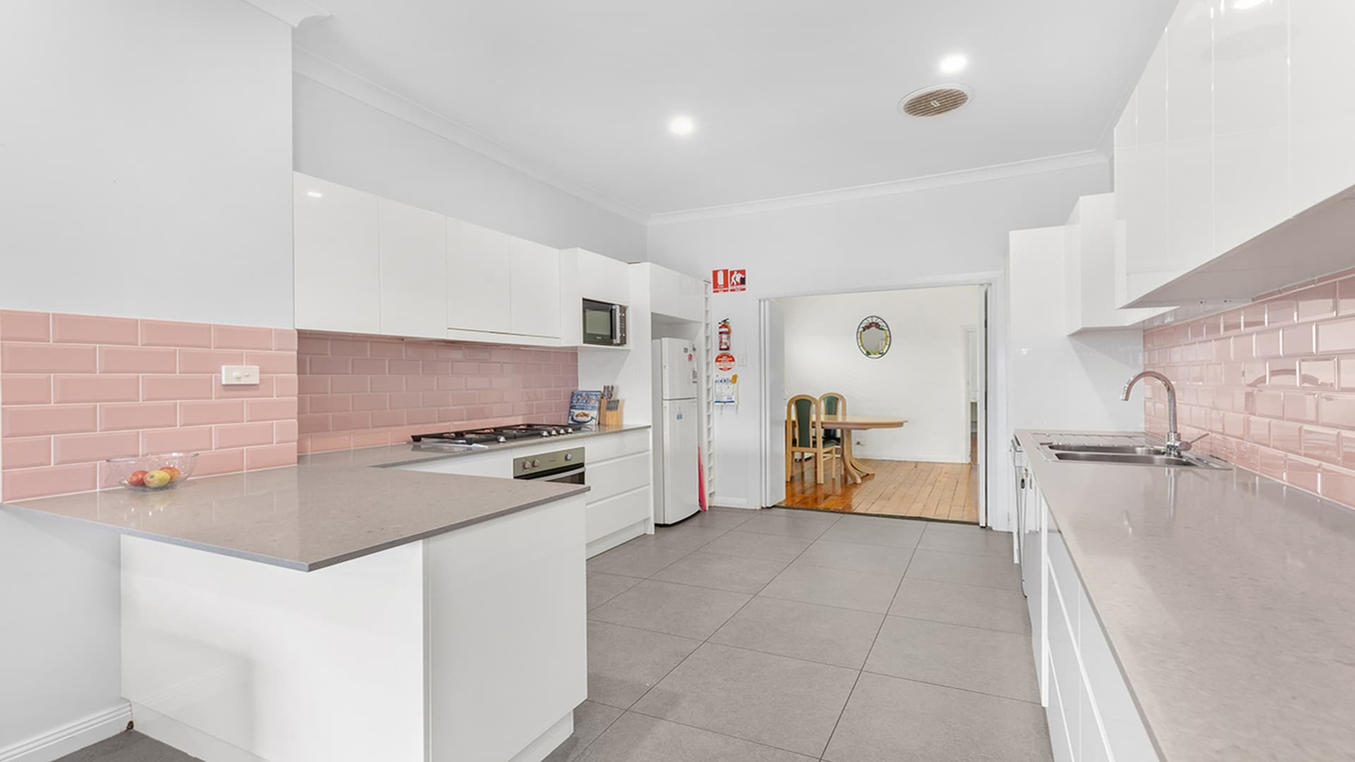 Large kitchen, easy access with lots of benches and pink tiled splash back.