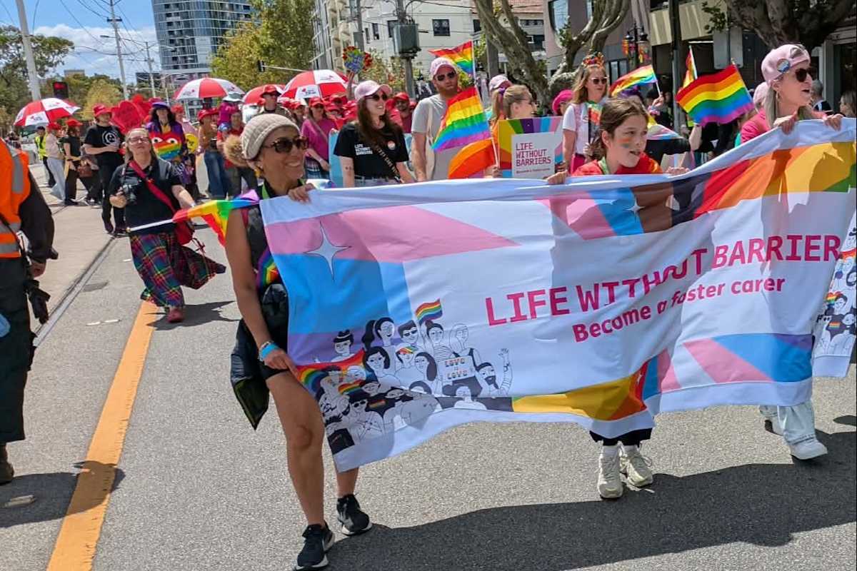 Staff and carers walking in the Midsumma Pride March, holding up the Life Without Barriers banner.