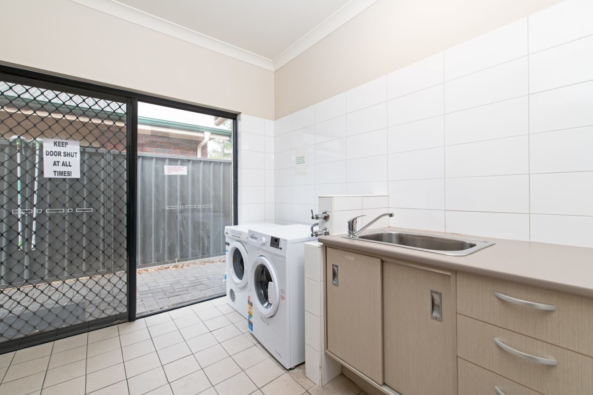 --Laundry with washing machine, dryer, bench and sink. Outdoor access through a sliding door.--