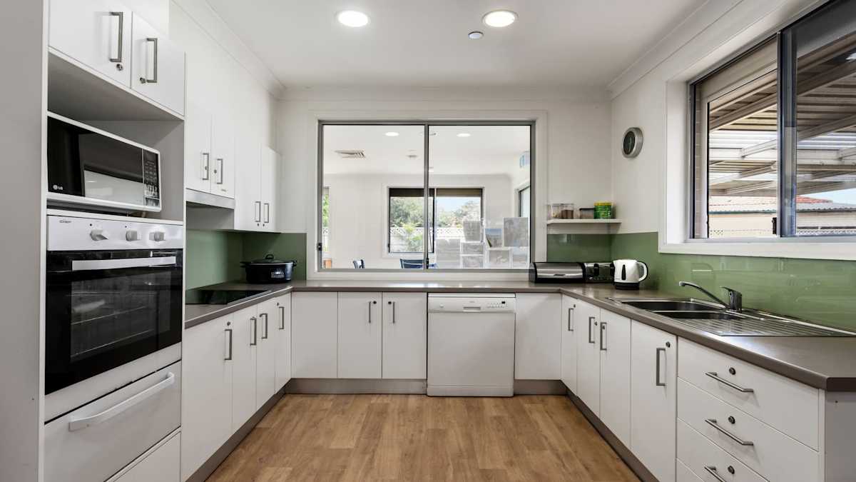 U-shaped kitchen with white cabinets, a dishwasher, induction stove and oven.