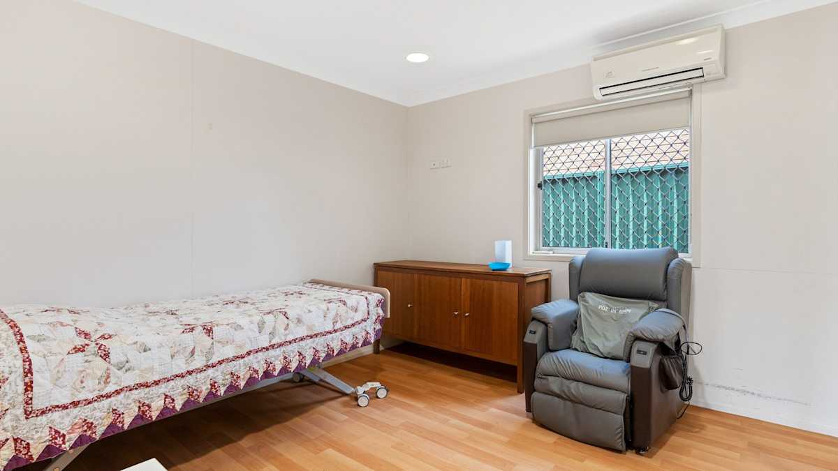 Bedroom with single bed, armchair, bedside table, wooden cabinet and air-conditioner.