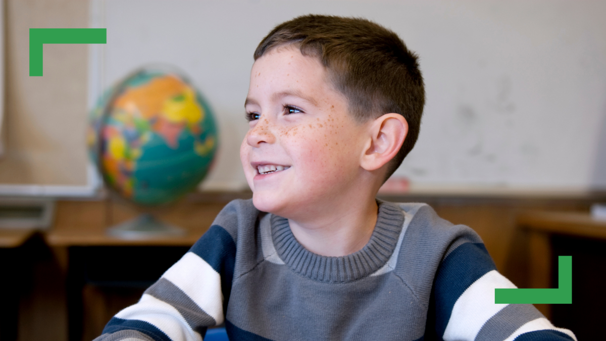 A close up of young boy wearing a striped jumper smiling and looking off to the side
