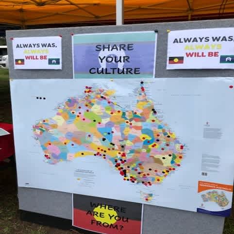 A map of Australia on a pinboard with signs around it instructing people to share their culture and pin where they are from on the map