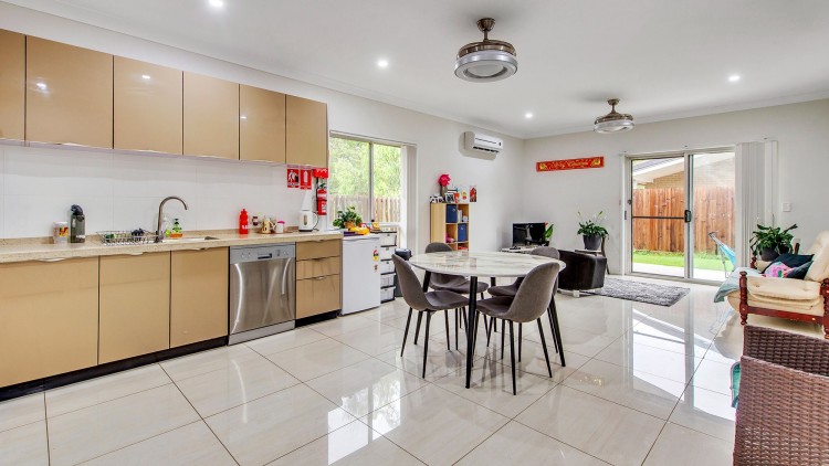 --Large bright kitchen. White tiled floor, wooden cabinets, round table, window doors.--