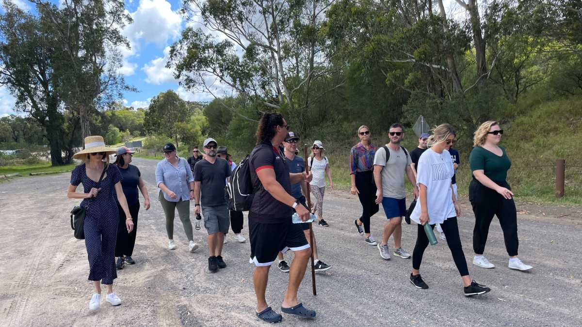 A group of Life Without Barriers staff being led through trees on the cultural walk. 