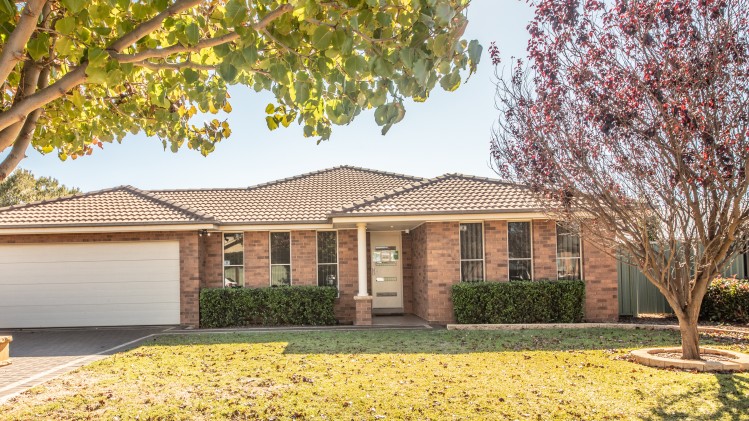 Front of brick house with trees and lawn. 