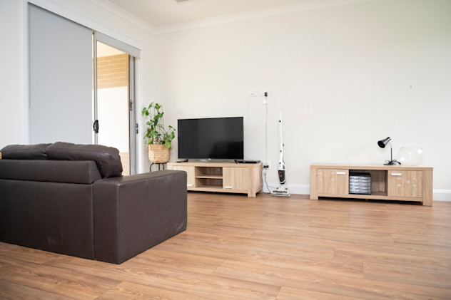 Lounge room with a couch, two TV stands and a TV unit.
