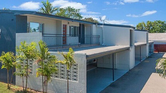 Front of duplex. Blue building with white details and palms out the front. 