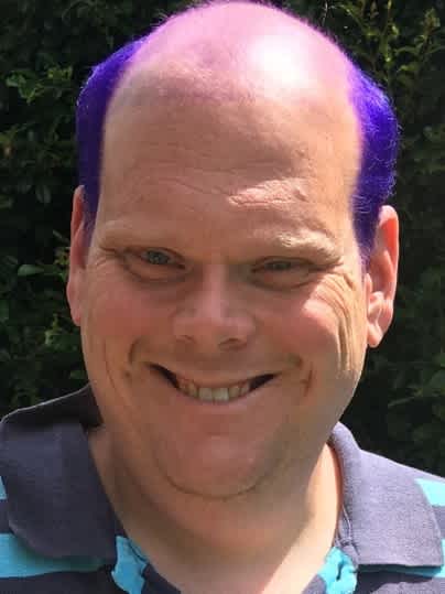 Jeremy smiling at the camera with purple hair.