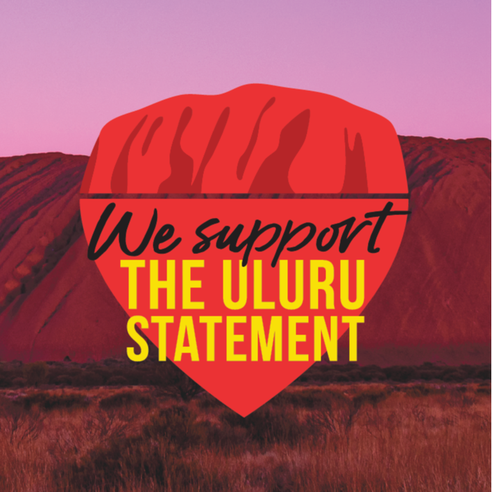 Background is a photo of Uluru. On top is a logo with Uluru drawn above text reading: We Support The Uluru Statement