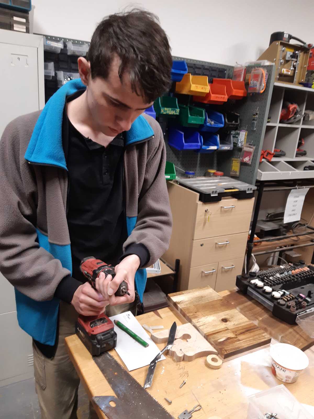 Sam in the Men's Shed holding a drill.