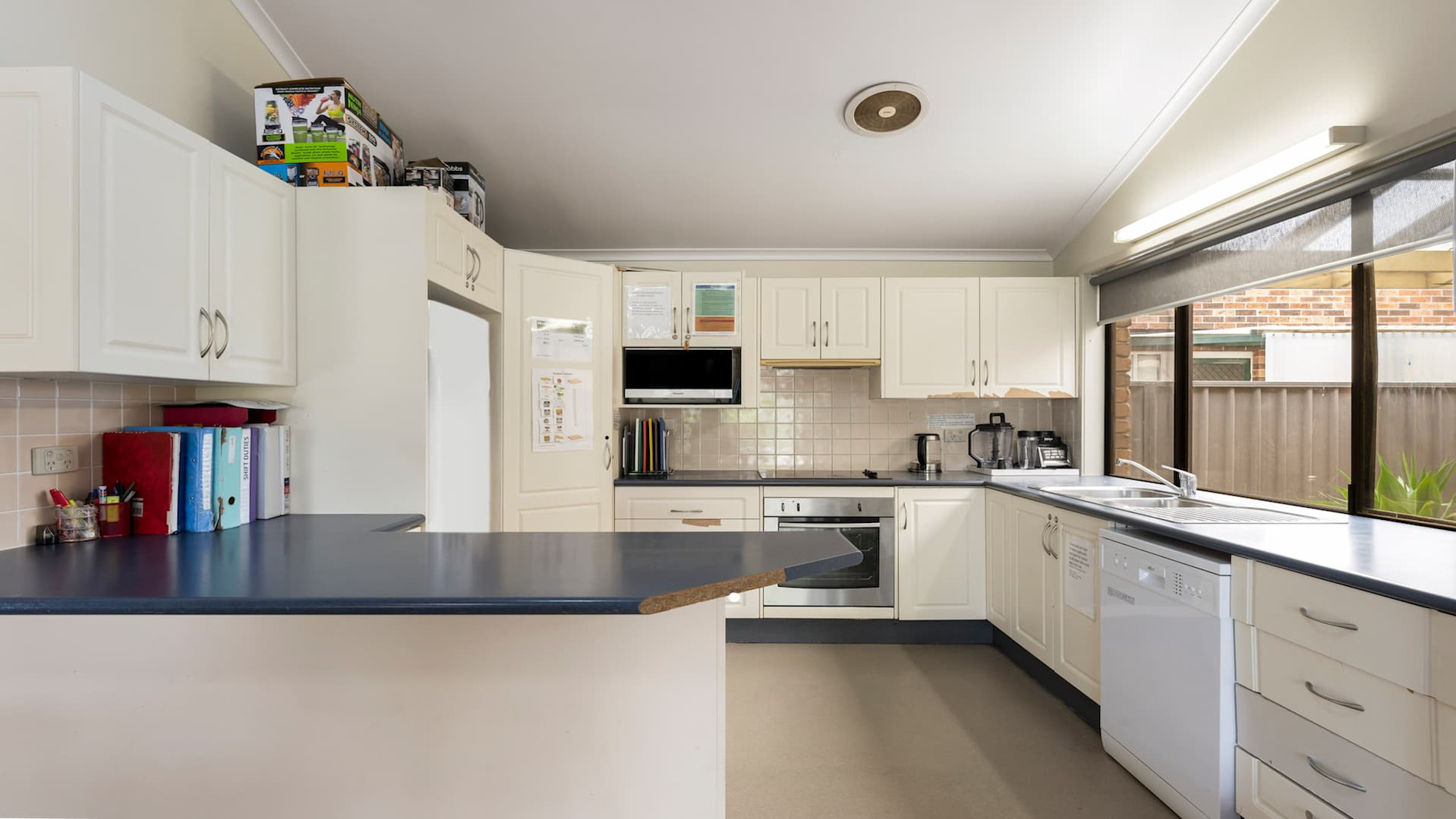 Kitchen with cream cabinets, dishwasher and oven.