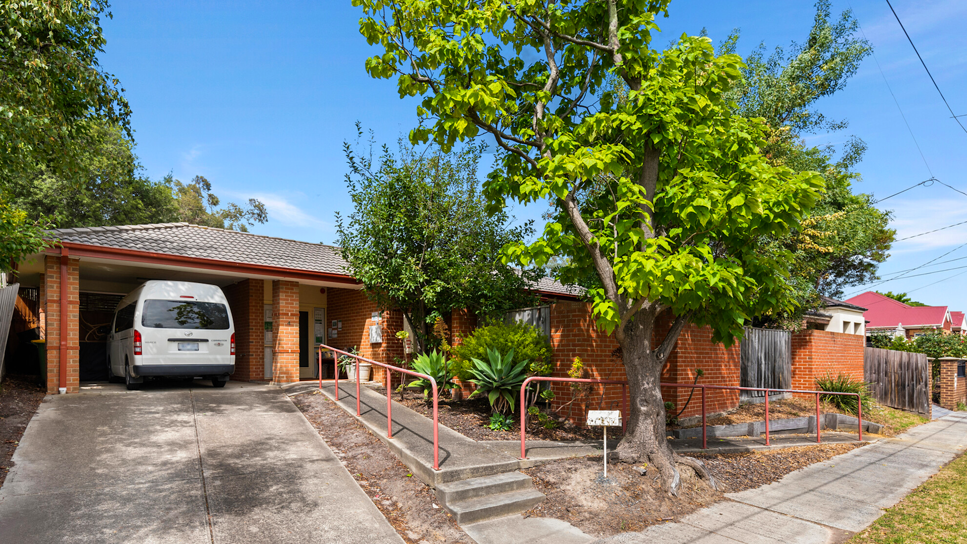 --Outside of one story home with stairs, a ramp and trees.--
