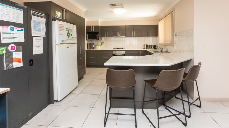 Large kitchen with dark cupboards and light bench tops. 