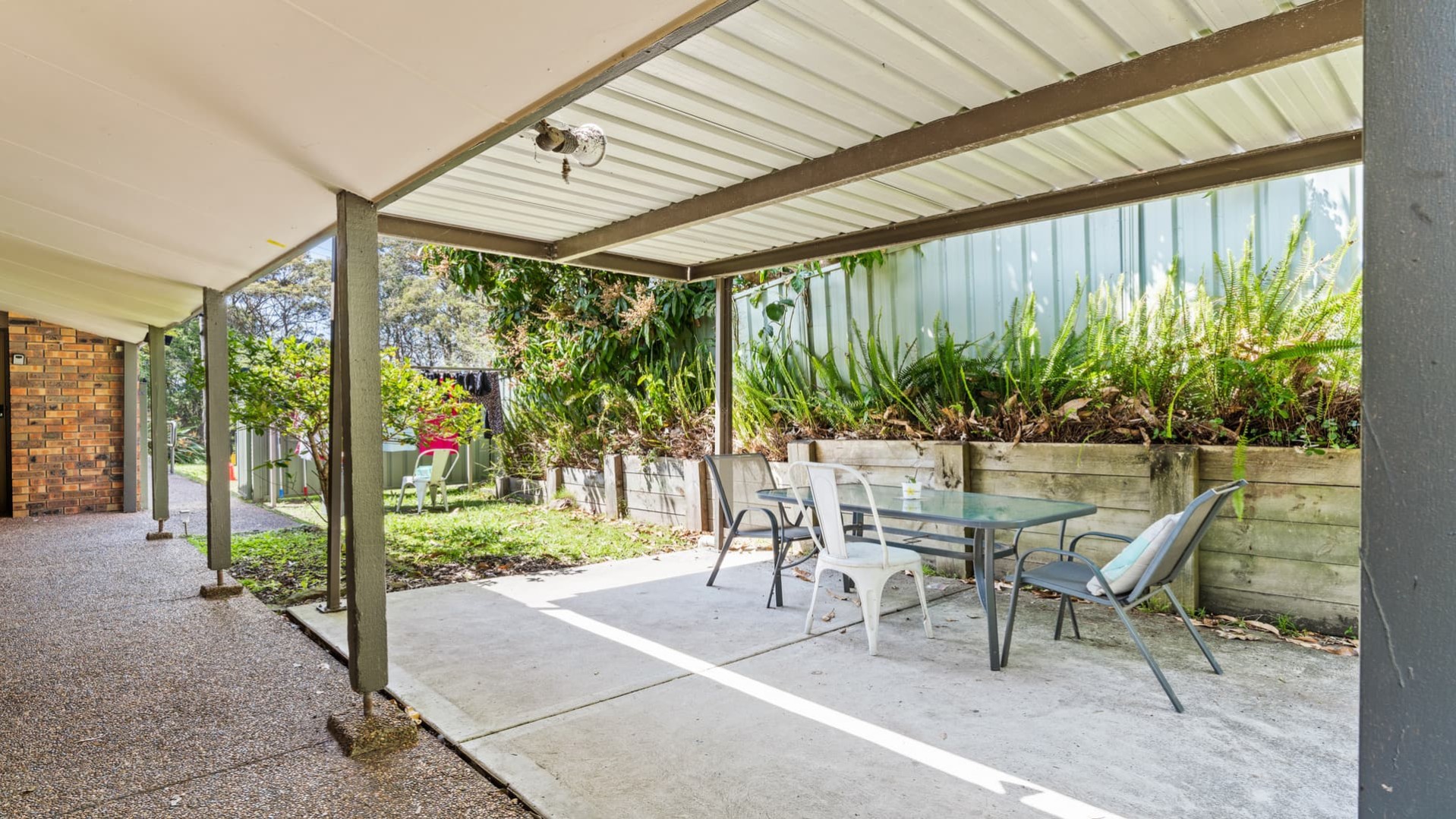 undercover back patio with chairs and table, gardens.