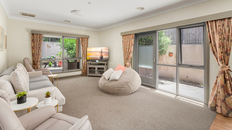 --Large beige living room with couches and beanbags. Large sliding doors.--