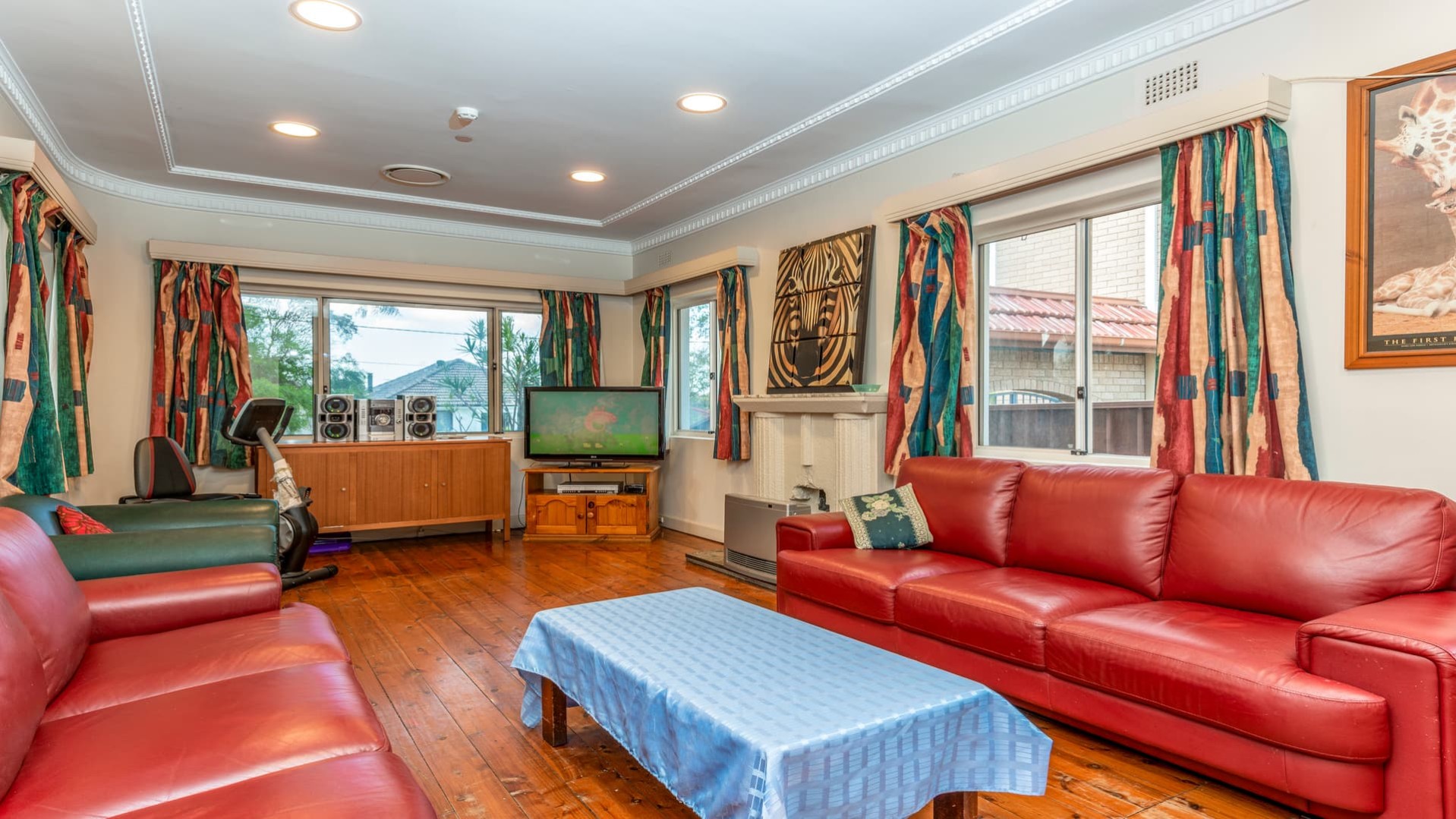 Spacious lounge area with red leather couches and armchairs. Large windows on both walls featured in the photos.  