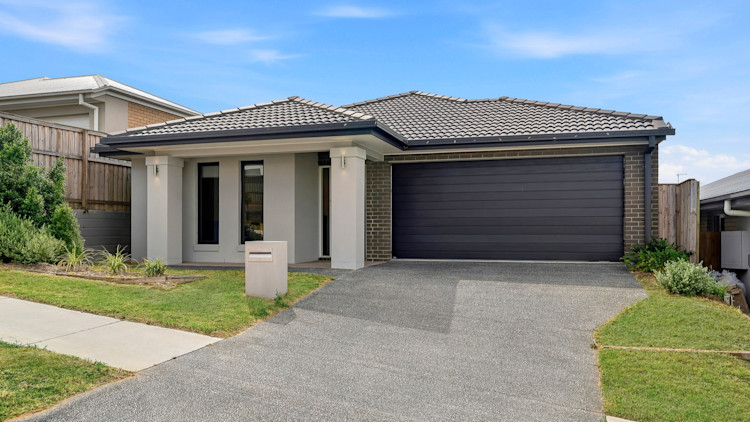 Front view of a modern single-storey home with a double garage, driveway and small lawn.