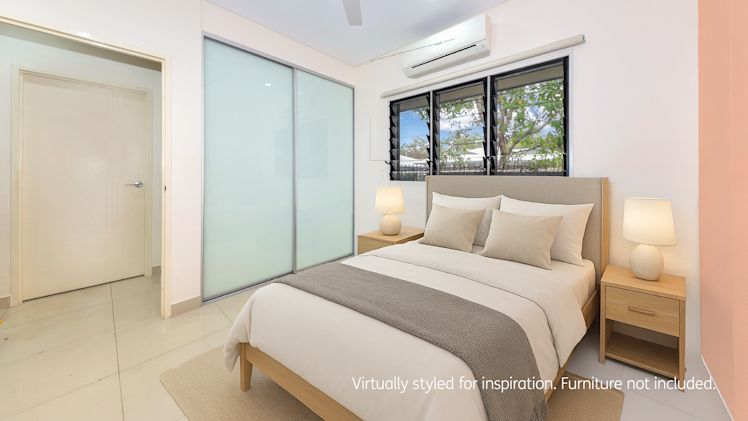 Bright and minimal bedroom with a queen bed, light timber furniture, soft lighting from bedside lamps, and large frosted sliding wardrobe doors.
