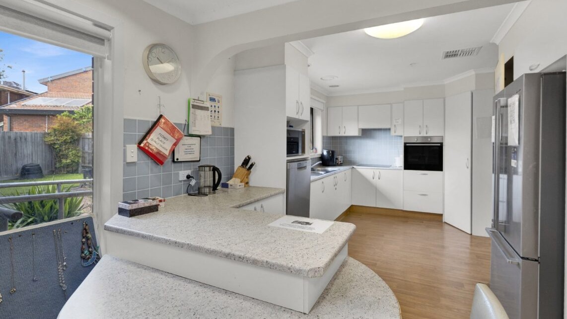 Spacious kitchen with island bench, cabinetry, and timber-look flooring.