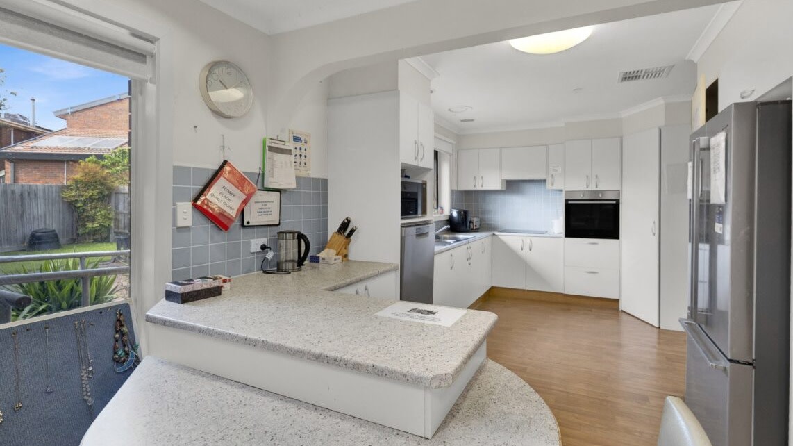 Spacious kitchen with island bench, cabinetry, and timber-look flooring.
