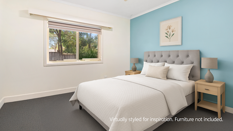 Modern bedroom with a light blue feature wall, tufted grey bed frame, white bedding, and matching wooden bedside tables with lamps.