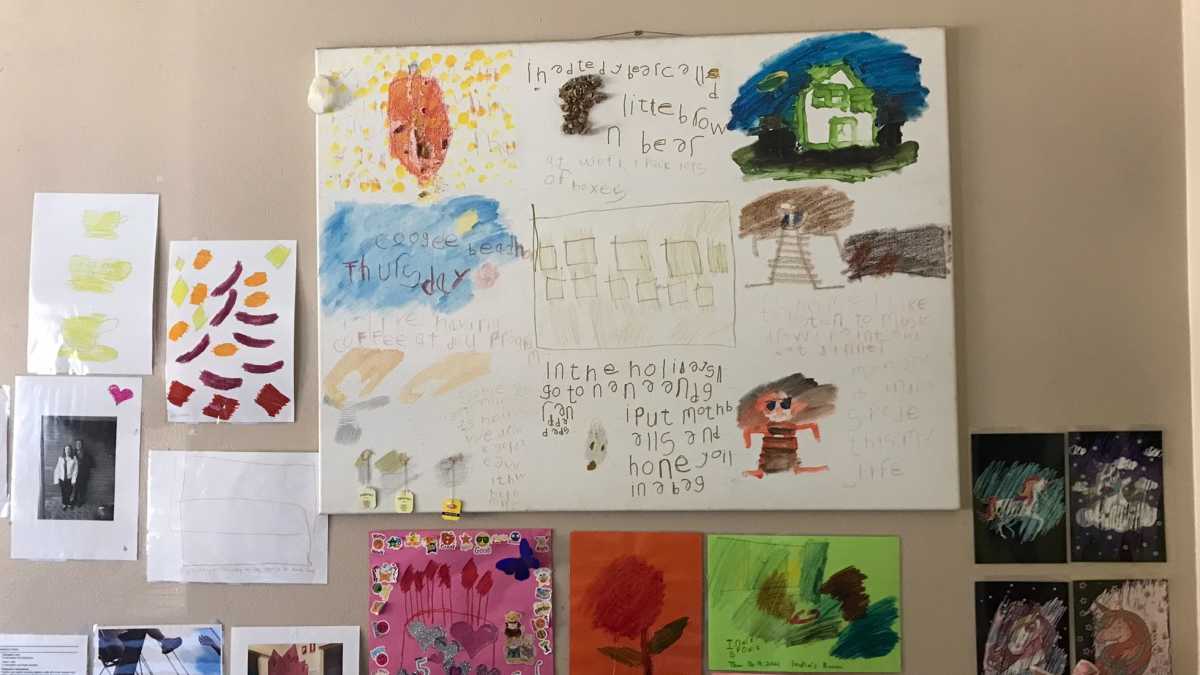 A wall with examples of Emily's artwork displayed on it.