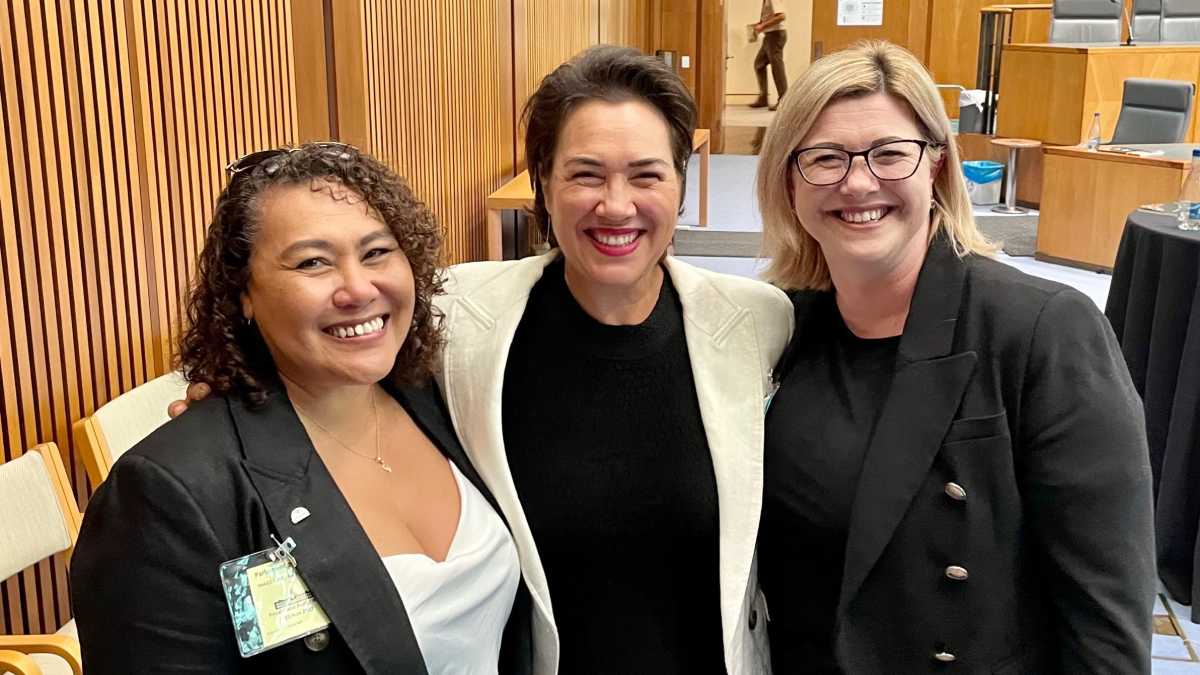 Karen, Catherine and Claire standing together smiling in a board room.