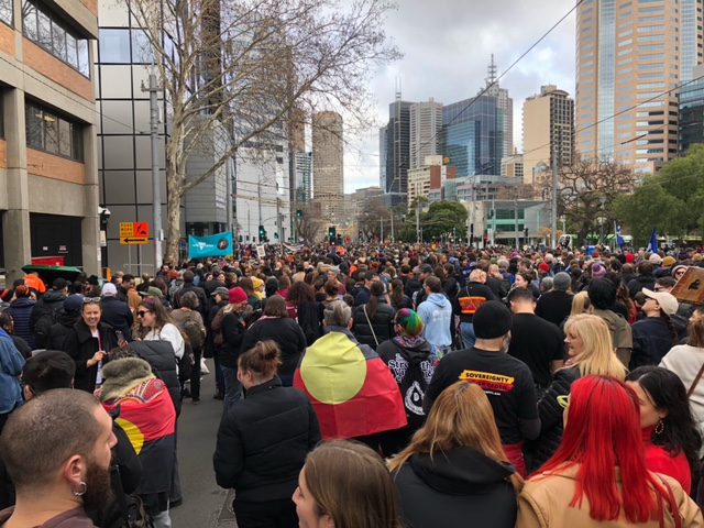 A large crowd walking down a city street as part of the NAIDOC March. 