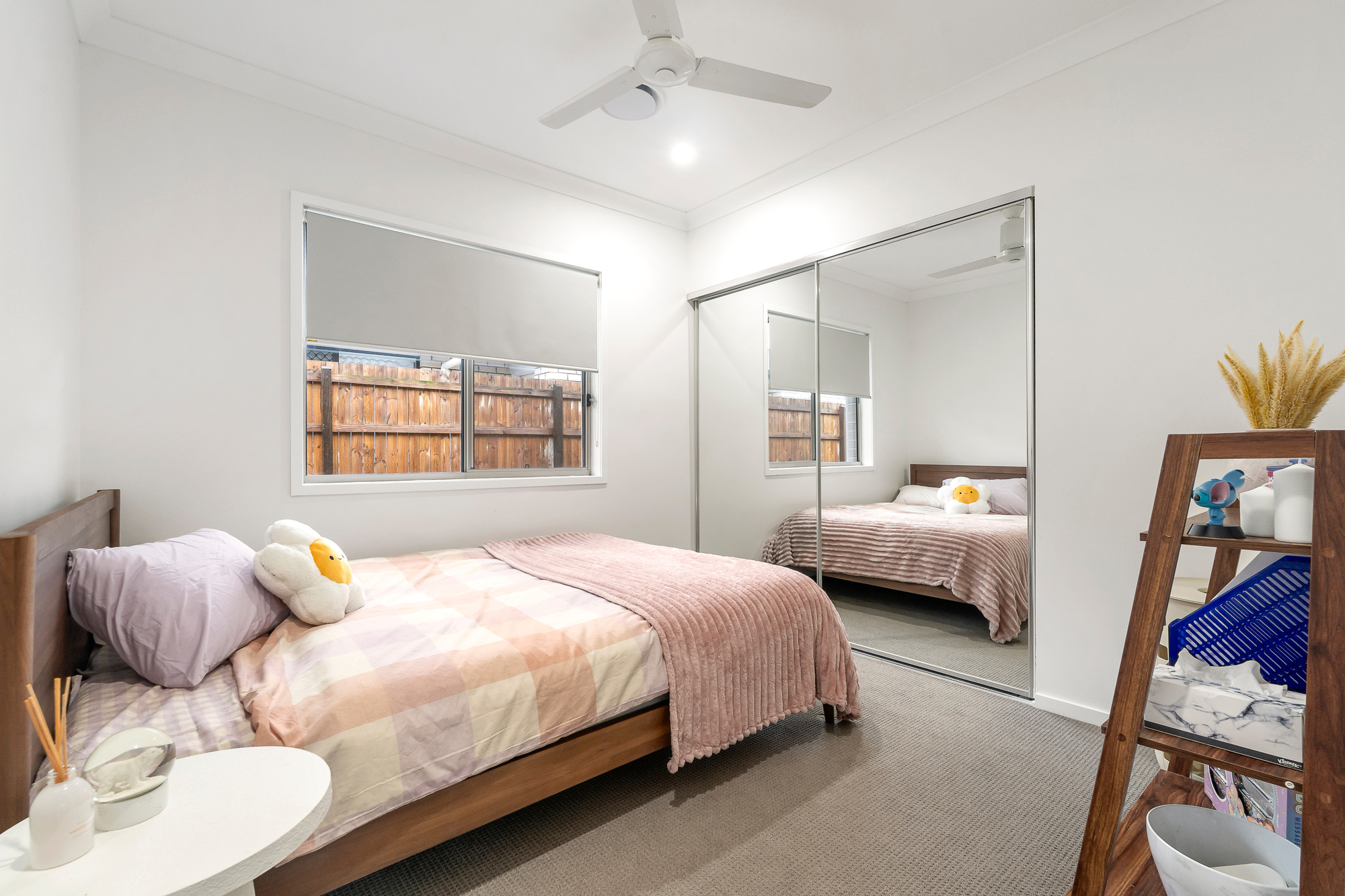 Cozy bedroom with a double bed, soft pink and beige bedding, mirrored wardrobe, and neutral décor.