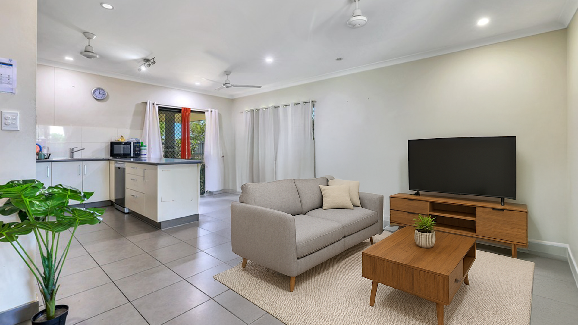 --Open plan lounge area with grey couch, wooden tv cabinet and coffee table