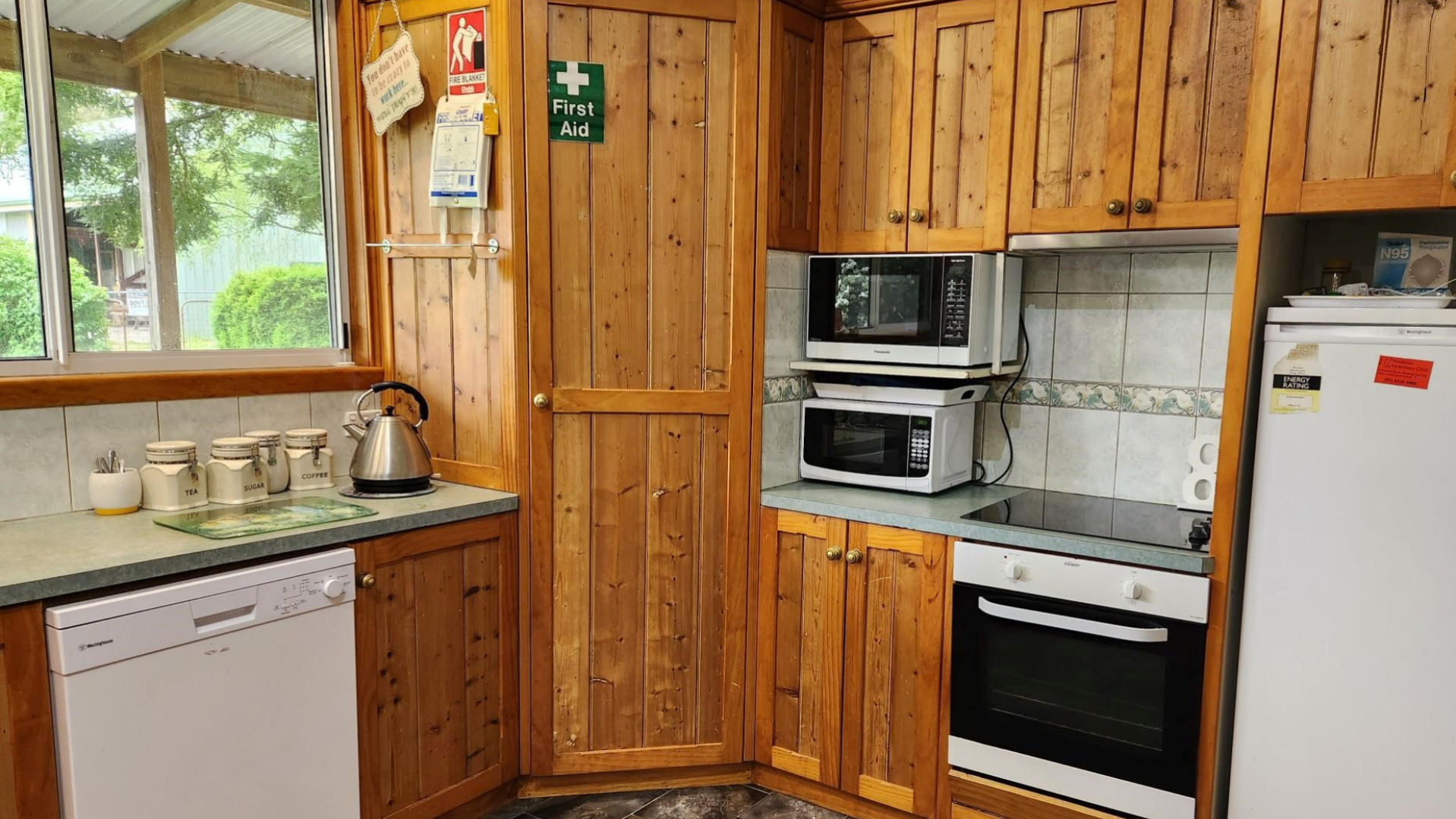 --Kitchen with wooden cupboards, a dishwasher, oven, stove and two microwaves.--