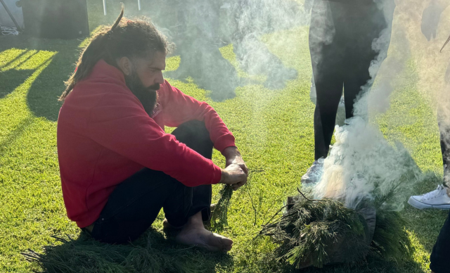 A man performs a smoking ceremony at the Shoalhaven NAIDOC event. 