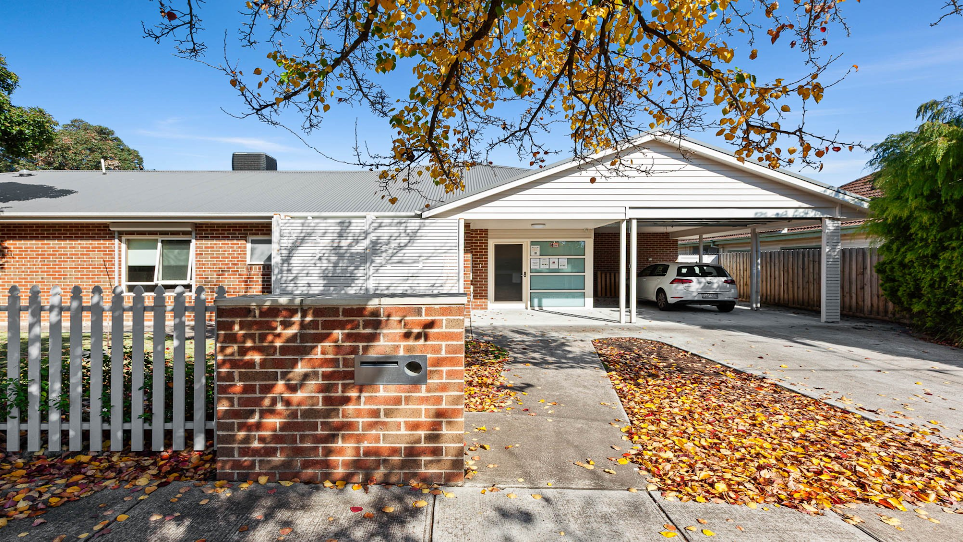 --Front of the house with a driveway leading to a car port.--