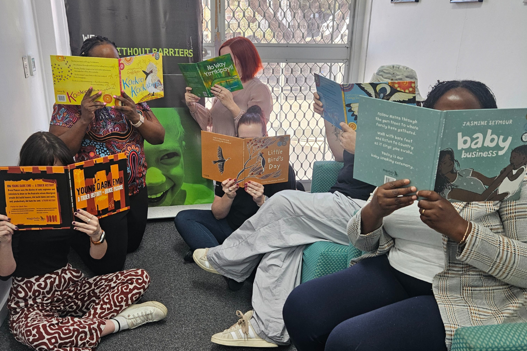 Townsville Child, Youth and Family team holding up books over their faces.