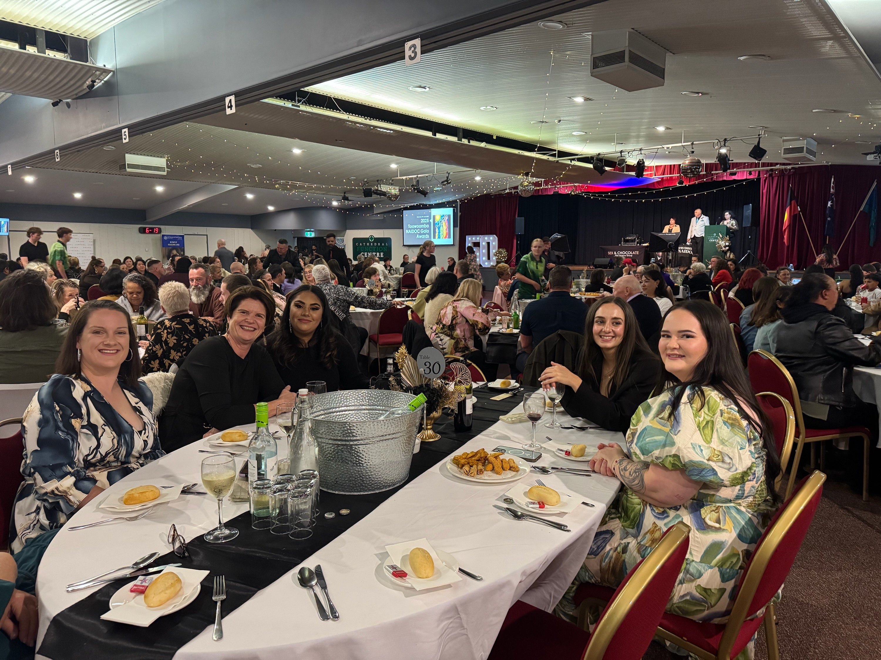 Staff sitting around a table at the gala dinner, smiling at the camera.