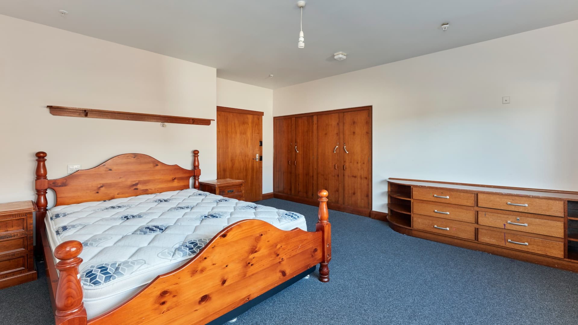 spacious bedroom, with wooden bed, mattress, wooden drawer set, side table, build in robe.