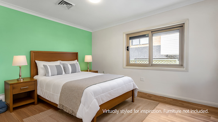 spacious bedroom with wooden flooring and light green wall.