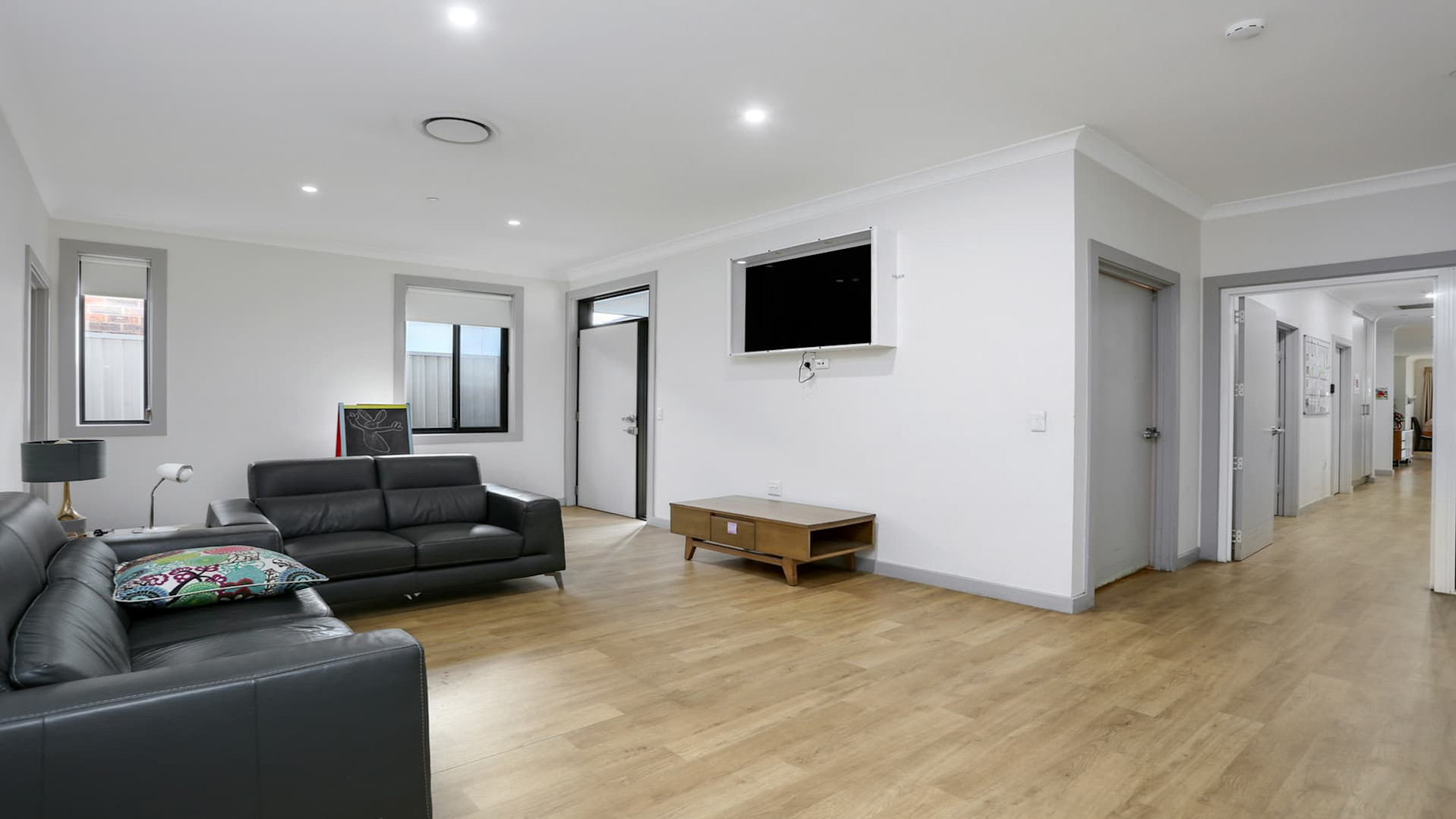 Second living space with leather couches facing a wall mounted television.