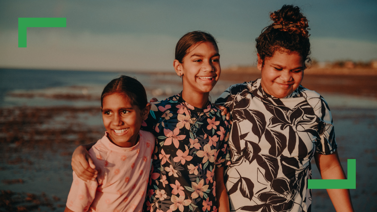 Three girls walking together at the beach.