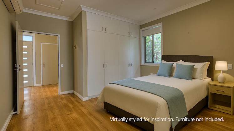 Modern bedroom featuring built-in white wardrobes, wood flooring, teal and white bedding, and a large window for natural light.